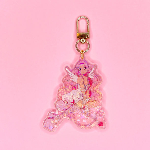 Acrylic keychain with star holographic finish and gold key ring. Artwork shows a beautiful cupid girl with bows in her hair and a bow and arrow with hearts.