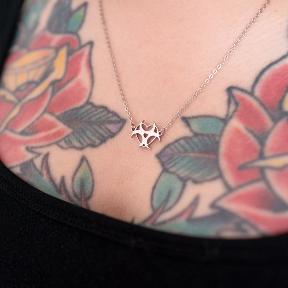 Silver necklace with bio-heart-zard symbol on tattooed model