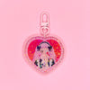 Acrylic keychain with star holographic finish and pastel pink key ring. Artwork shows a creepy cute girl with pink hair and eyepatch holding a creepy stuffed bunny.