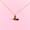 Gold necklace pendant of a silhouette of a witch and cat flying on a broom.