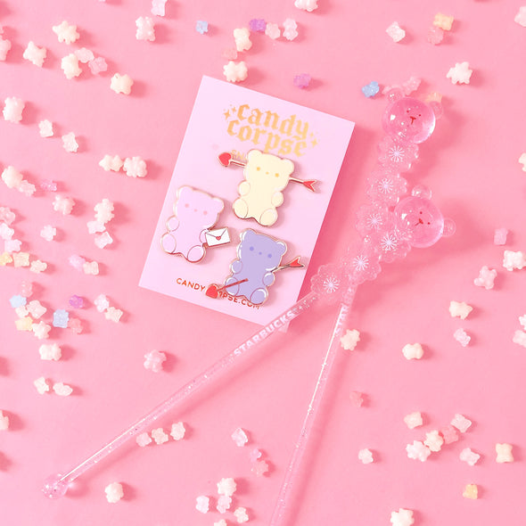 Gummi bear enamel pins on a pink background with candy sprinkles on the background