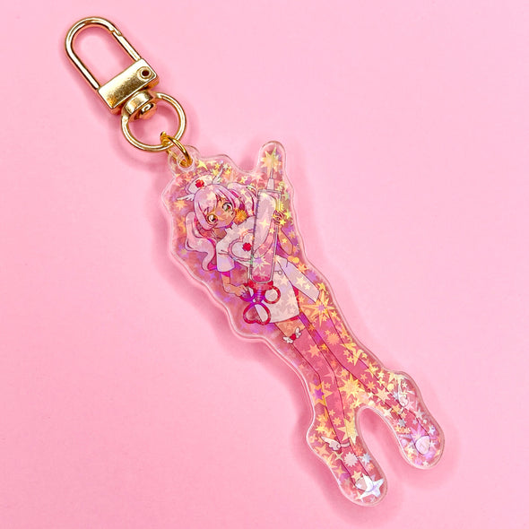 Acrylic keychain with star holographic finish and gold key ring. Artwork shows an adorable nurse with pink hair holding an oversized syringe with hearts.