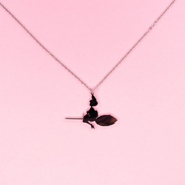 Silver necklace pendant of a silhouette of a witch and cat flying on a broom.