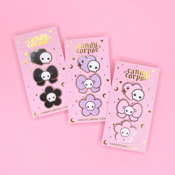 Creepy cute skull themed enamel pin sets on pink and gold foil backing cards